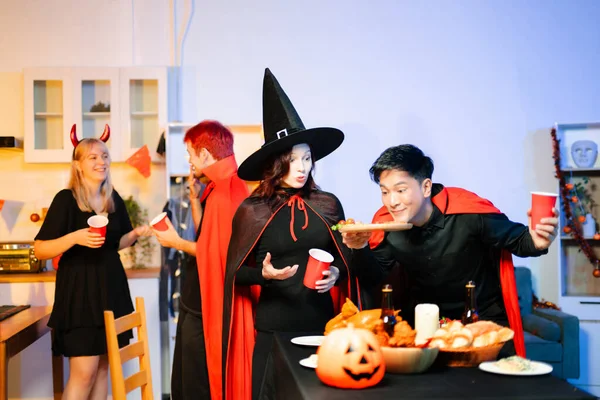 Cadılar Bayramı kostümlü genç arkadaşlar kapalı bir partide balkabağı feneri süslüyorlar. Gerçek insanlar ürkütücü titreşimleri, kırmızı bardakları, atıştırmalıkları ve Cadılar Bayramı aksesuarlarını severler..