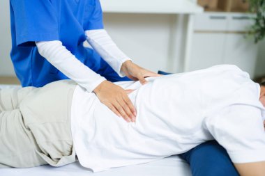 Hemşire klinikteki yaşlı hastaya sırt masajı yapıyor. Fizyoterapi, rehabilitasyon, yaşlanma, sağlık, ağrı kesici ve profesyonel sağlık konuları için mükemmel.