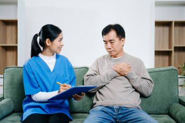 Sağlık hemşiresi ev ziyaretindeki yaşlı adama rapor vermeyi açıklıyor. Yaşlı konsültasyonunda bir anlık bakım, güven ve netlik. Tıbbi tartışma konseptinde gerçek insanlar