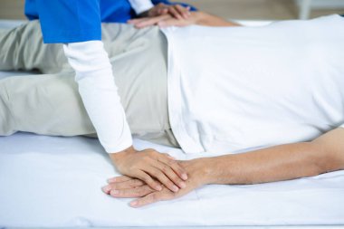 Bakıcı terapist, kıdemli hastaya el ele tutuşarak destek olur. Sağlık, yaşlı bakımı, rehabilitasyon, duygusal iyileşme, insan dokunuşu ve tıbbi ortamlara güven.