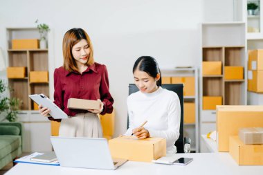 İki Asyalı girişimci paketlerini hazırlar ve bir e-ticaret şirketinin siparişlerini yönetir. Takım çalışması, çevrimiçi dükkan, başlangıç, dağıtım ve küçük işletme temaları için mükemmel.