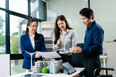 Bir toplantıda rüzgar türbini sunan ve modeller yapan profesyoneller. Yeşil enerji, akıllı şehir planlaması ve sürdürülebilir iş temaları için ideal.