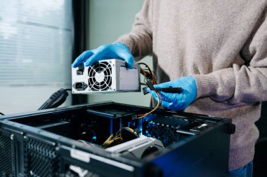 Masaüstü bilgisayar montajı sırasında güç kaynağı ve kablolarıyla ilgilenen eldiven teknisyeni. Bilgisayar onarımı, PSU kurulumu ve donanım güvenliği gibi konular için mükemmel.