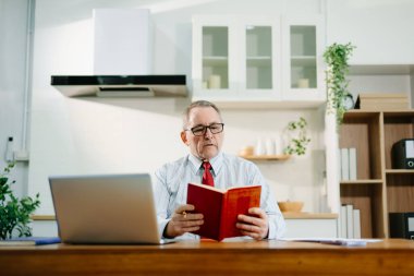 Olgun iş adamı evde otururken dizüstü bilgisayar kullanıyor. man sitti