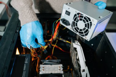 Masaüstü bilgisayar montajı sırasında güç kaynağı ve kablolarıyla ilgilenen eldiven teknisyeni. Bilgisayar onarımı, PSU kurulumu ve donanım güvenliği gibi konular için mükemmel.