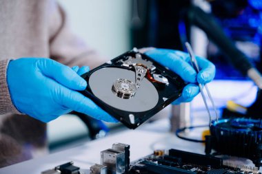 Teknisyenin masasında sabit disk ve bir bilgisayar ana kartı var. Veri, donanım ve bilgi teknolojisi kavramı.