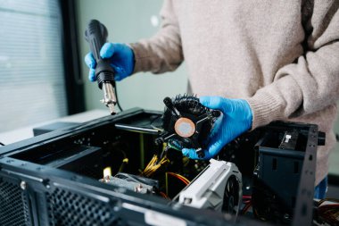 İşlemci soğutucusu ve ısı tabancasını masaüstü bilgisayarı üzerinde tutan eldivenli teknisyenlere yakın çekim. Bilgisayar onarımı, soğutma sistemi ve donanım bakım kavramları için ideal resim.