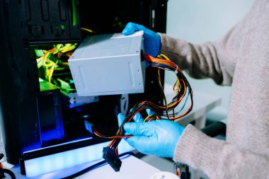 Masaüstü bilgisayar montajı sırasında güç kaynağı ve kablolarıyla ilgilenen eldiven teknisyeni. Bilgisayar onarımı, PSU kurulumu ve donanım güvenliği gibi konular için mükemmel.