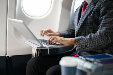 Birinci sınıfta dizüstü bilgisayar kullanan kendine güvenen bir iş adamı, üretkenliği, lüks seyahatleri ve iş hayatında başarılı olmak için modern dijital yaşam tarzını harmanlıyor..