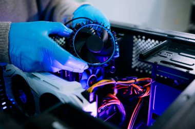 İşlemci soğutucusu ve ısı tabancasını masaüstü bilgisayarı üzerinde tutan eldivenli teknisyenlere yakın çekim. Bilgisayar onarımı, soğutma sistemi ve donanım için ideal resim