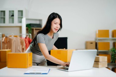 Başlangıçta küçük işletme KOBİ 'si, akıllı telefon veya tablet kullanan girişimci sahibi kadın çevrimiçi alışveriş siparişini alıp kontrol ediyor