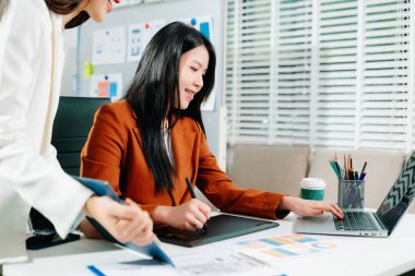 İki yaratıcı kadın tasarımcı modern bir ofiste renk paletleri ve UX UI projesini tartışıyor. Takım çalışması, yenilik ve dijital tasarım temaları için mükemmel.