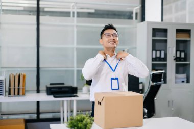 Asyalı bir ofis çalışanı eşyalarını karton bir kutuya koyup istifayı, iş değişikliğini ya da modern bir iş ortamında yeni bir kariyeri temsil ediyor..