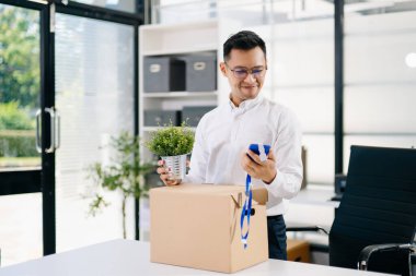 Asyalı bir ofis çalışanı eşyalarını karton bir kutuya koyup istifayı, iş değişikliğini ya da modern bir iş ortamında yeni bir kariyeri temsil ediyor..