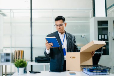 Hüzünlü işadamı işten çıkarılma üzerine kutu ve kimlik kartıyla ofiste oturuyor. İş kaybı ve iş stresi yüzünden kendini yorgun ve depresif hissediyor..