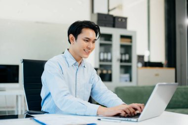 Asyalı adam çalıştığı yerde bilgisayarını ve tabletini kullanıyor. İşine odaklan..