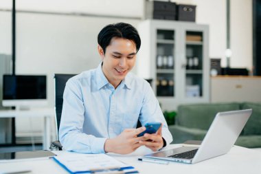 Asyalı adam çalıştığı yerde bilgisayarını ve tabletini kullanıyor. İşine odaklan..