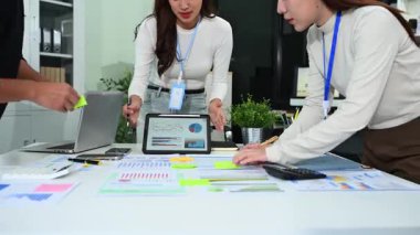 Çağdaş bir ofis içinde finansal istatistikleri tartışan bir grup genç işletme uzmanı