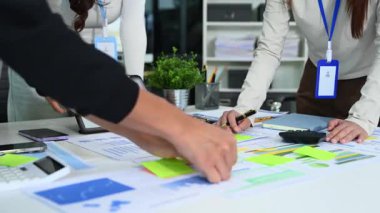 Çağdaş bir ofis içinde finansal istatistikleri tartışan bir grup genç işletme uzmanı