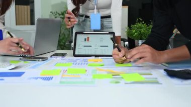 Parlak, açık planlı bir ofiste finansal raporlar üzerinde çalışan çeşitli genç analistler.