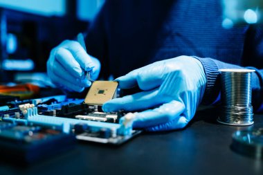 Asyalı bir erkek mühendis hasarlı bir elektronik cihaza işlevsellik kazandırmak için profesyonel laboratuvar ekipmanları kullanır..