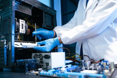 Orta yaşlı Asyalı mühendis profesyonel bir teknik tesiste donanım sorunlarını çözerken hassasiyet ve beceri gösteriyor.