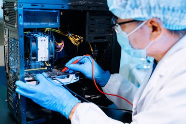 Deneyimli bir Asyalı elektronik mühendisi yüksek teknoloji laboratuvar ortamında karmaşık bir devre kartını dikkatlice tamir eder..