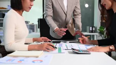 Finansal performans ve veri istatistiklerini incelemek için bir hesap makinesi ve dijital tablet kullanan ellerin yakın görüntüsü.