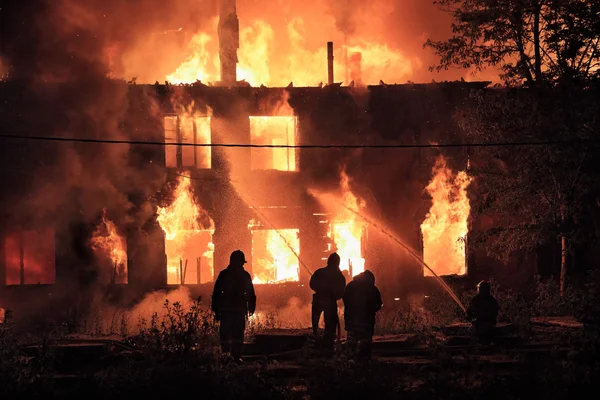 Silhuetas de bombeiros no fundo de fogo — Fotografia de Stock