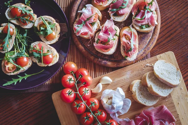 Bruschetta aux tomates cerises, prosciutto, ail, huile d'olive Images De Stock Libres De Droits