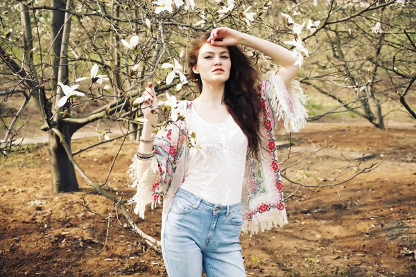 Genç güzel kadın çiçek açan Manolya bahçede poz model.