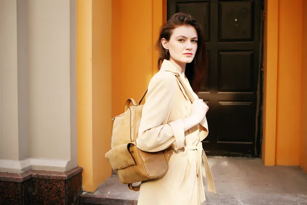Young stylish hipster girl wearing modern trench coat walking in urban city smiling happy. 
