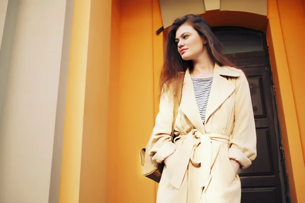 Joven chica hipster elegante con gabardina moderna caminando en la ciudad urbana sonriendo feliz . —  Fotos de Stock