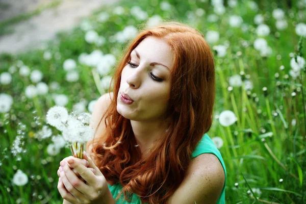 Retrato de estilo de vida de una joven mujer de moda de primavera que sopla diente de león en el jardín de primavera . — Foto de Stock