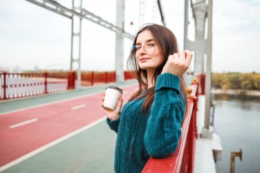 Şehirde bir fincan kahveyle kırmızı paltolu genç bir kadın