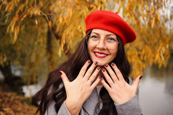 幸せなブルネット女性でスタイリッシュな赤ベレー帽 赤唇とBordaux爪 — ストック写真