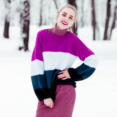 Kar parkında süveter giyen genç bir kadın.