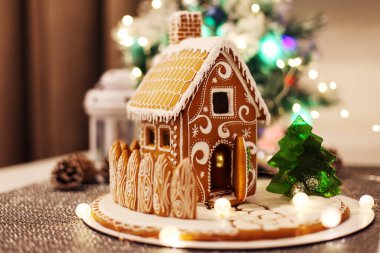 Noel süslemeli köknar ağacının sönmüş ışıkları üzerine zencefilli kurabiye evi. 