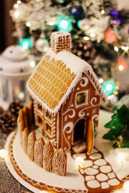 Noel süslemeli köknar ağacının sönmüş ışıkları üzerine zencefilli kurabiye evi. 