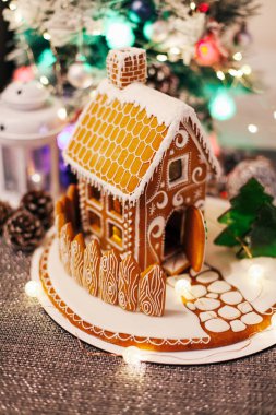 Noel süslemeli köknar ağacının sönmüş ışıkları üzerine zencefilli kurabiye evi. 