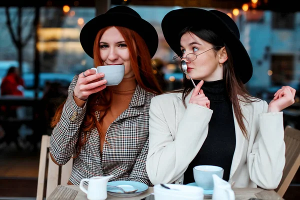 Two girl friends drinking coffee in the cafe