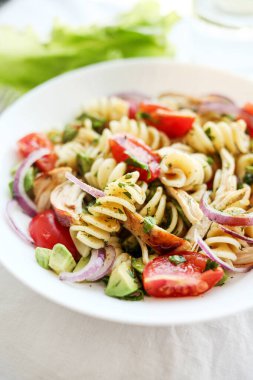 Domates, avokado, chiken ve kırmızı soğanlı makarna salatası.