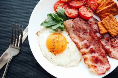 İngiliz kahvaltısı - kızarmış yumurta, domates, pastırma ve kraker