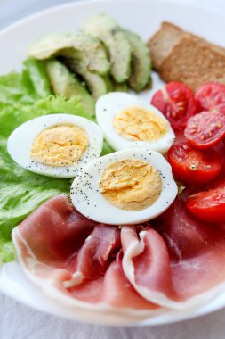 Haşlanmış yumurta, pastırma, avokado, tost, domates ve salata.