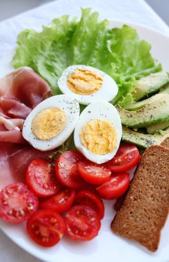 Haşlanmış yumurta, pastırma, avokado, tost, domates ve salata.