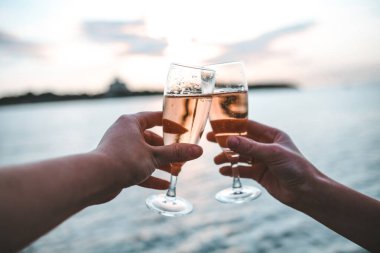 Çift gün batımında iki bardak gül şarabıyla şıngırdıyor.