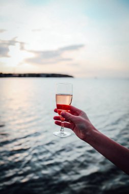 Ellerinde bir bardak soğuk gül şarabı tutan bir kız.