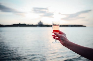 Ellerinde bir bardak soğuk gül şarabı tutan bir kız.