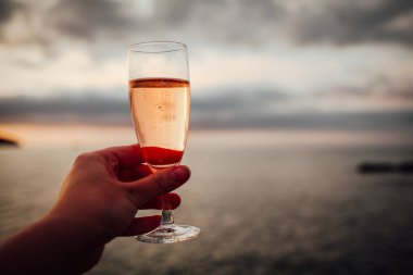 Ellerinde bir bardak soğuk gül şarabı tutan bir kız.