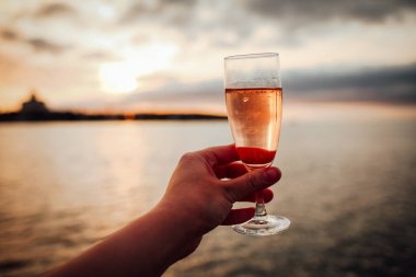 Ellerinde bir bardak soğuk gül şarabı tutan bir kız.